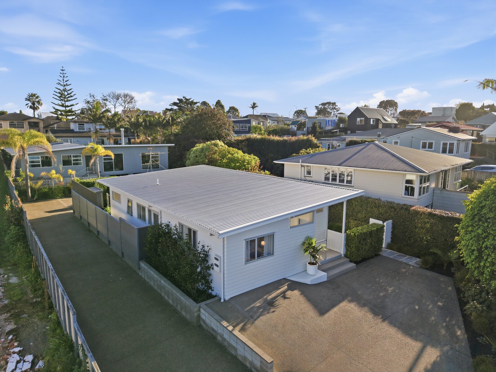 Elevated view of a detached Auckland home and surrounding residential neighbourhood -->